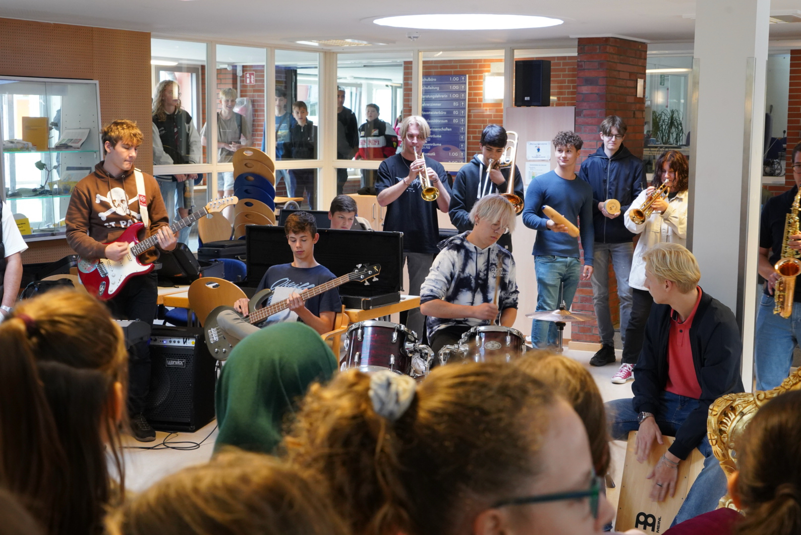 Eine Schülerband mit Trompeten, E-Gitarre, E-Bass und Schlagzeug spielt in der Pausenhalle